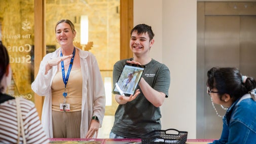 Nexus School with special education needs teenagers around a table at the Conservation Studio at Knole, Kent with a glass door and lift in the background